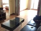 Spacious living room with hardwood floors, large sofa, and glass table