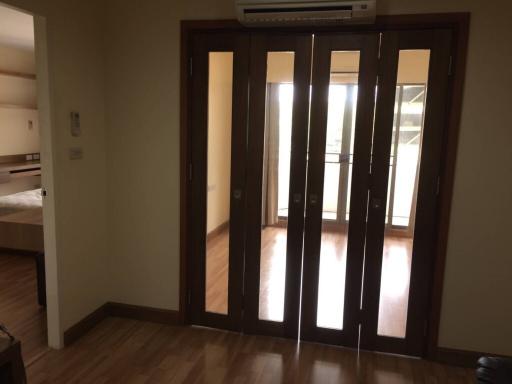 Spacious bedroom with hardwood floors and glass doors leading to another room