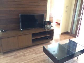 Spacious living room with wooden flooring, modern TV cabinet, and glass coffee table