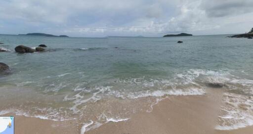 Serene beachfront view with clear waters and distant islands