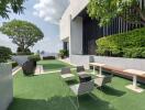 Modern rooftop garden with city skyline view, artificial grass, comfortable seating area, and well-maintained plants