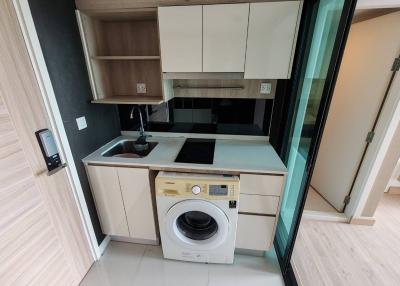 Compact modern kitchen with built-in appliances and laundry machine