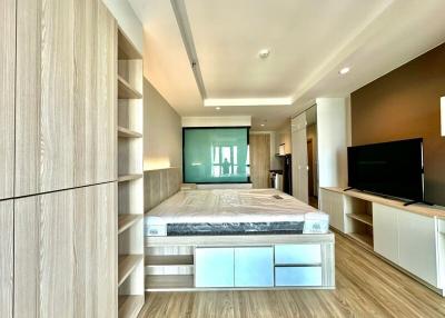 Modern bedroom interior with king-sized bed, wood flooring, and flat-screen TV