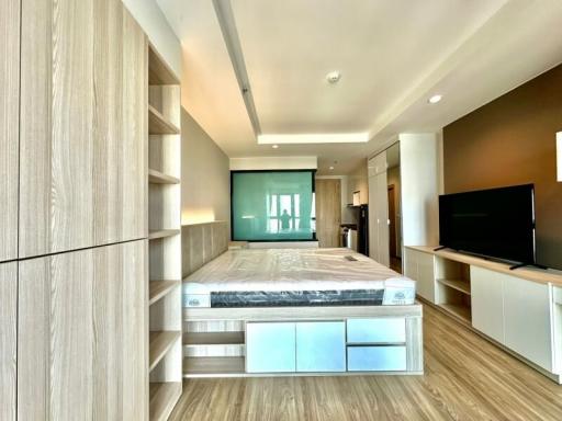 Modern bedroom interior with king-sized bed, wood flooring, and flat-screen TV