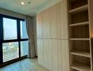 Modern bedroom interior with a large window, built-in wardrobe and empty bookshelves