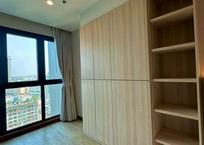Modern bedroom interior with a large window, built-in wardrobe and empty bookshelves