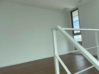 Spacious and brightly lit empty room with wooden floors and a large window