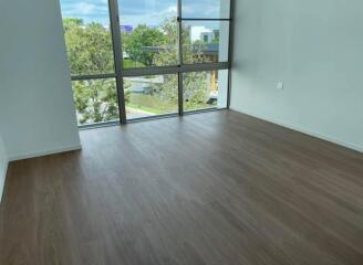 Empty interior of a modern building with large windows and hardwood flooring