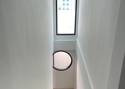 Modern staircase with white walls and wooden steps leading to a bright window