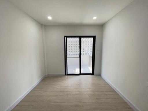 Empty bedroom with wooden flooring and glass door