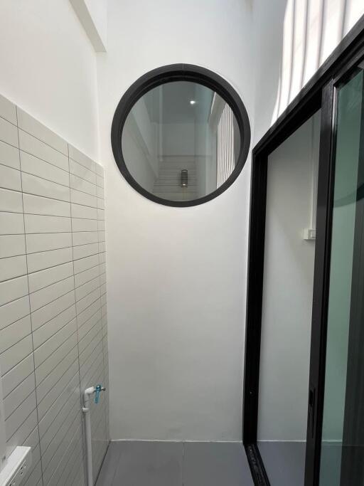 Modern bathroom interior with round mirror and glass door