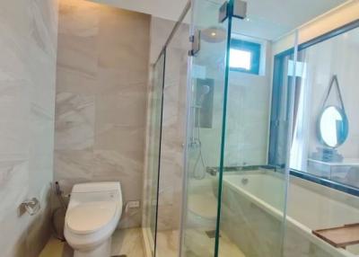 Modern bathroom interior with glass shower compartment, bathtub, and toilet