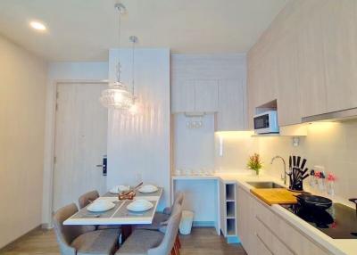 Modern kitchen with dining space featuring elegant light fixture and contemporary design