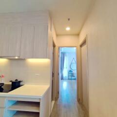 Modern kitchen with wooden cabinetry and open doorway leading to adjacent room