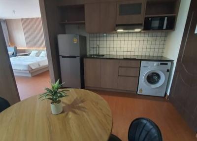 Studio apartment kitchen with modern appliances and bedroom in the background