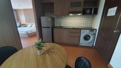 Studio apartment kitchen with modern appliances and bedroom in the background