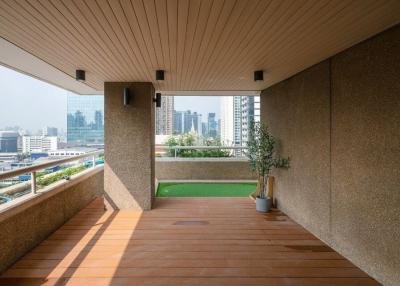 Spacious balcony with wooden flooring, artificial grass area and a city view