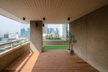 Spacious balcony with wooden flooring, artificial grass area and a city view