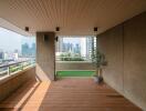 Spacious balcony with wooden flooring, artificial grass area and a city view