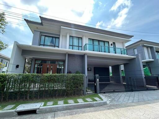 Modern two-story house with a gray facade, large windows, and a covered carport