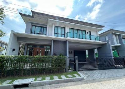 Modern two-story house with a gray facade, large windows, and a covered carport