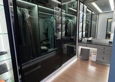 Modern walk-in closet with glass doors and wooden floors