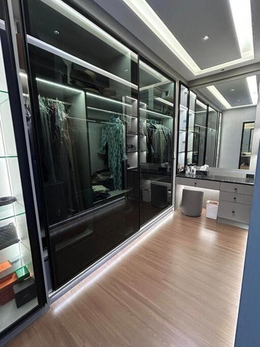 Modern walk-in closet with glass doors and wooden floors