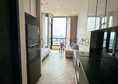 Modern kitchen with sleek black appliances leading to a bright living room with large windows and a view