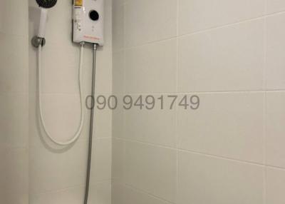 White tiled bathroom showing a wall-mounted electric shower unit