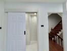 Modern interior space with white doors, wooden flooring, and access to the staircase