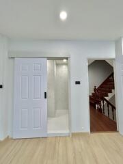 Modern interior space with white doors, wooden flooring, and access to the staircase