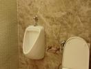 Marble tiled bathroom with a urinal and toilet