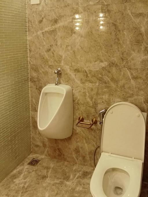 Marble tiled bathroom with a urinal and toilet