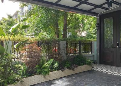 Covered entrance of a modern home with lush greenery and a patterned tile floor