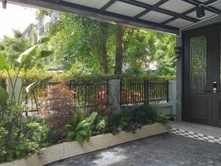 Covered entrance of a modern home with lush greenery and a patterned tile floor