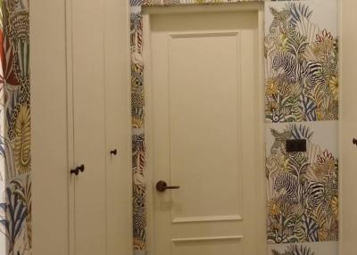 Hallway with tropical wallpaper design and white door
