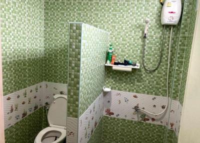Compact bathroom with green tiles and electric shower