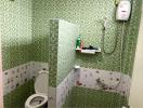 Compact bathroom with green tiles and electric shower