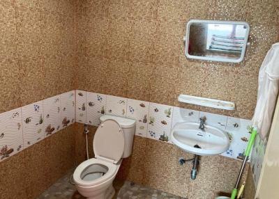Compact bathroom with patterned tiles, toilet, and sink