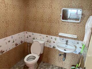 Compact bathroom with patterned tiles, toilet, and sink