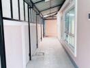 Covered residential corridor with tiled flooring and windows