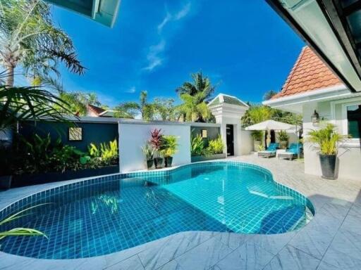 Private swimming pool with tropical plants and a sunny blue sky
