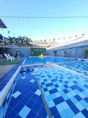 Private outdoor swimming pool with clear blue water, surrounded by a tiled deck and festive bunting decorations