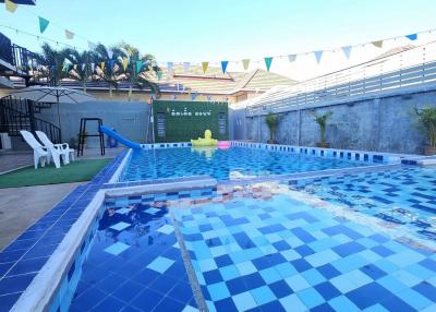 Private outdoor swimming pool with clear blue water, surrounded by a tiled deck and festive bunting decorations