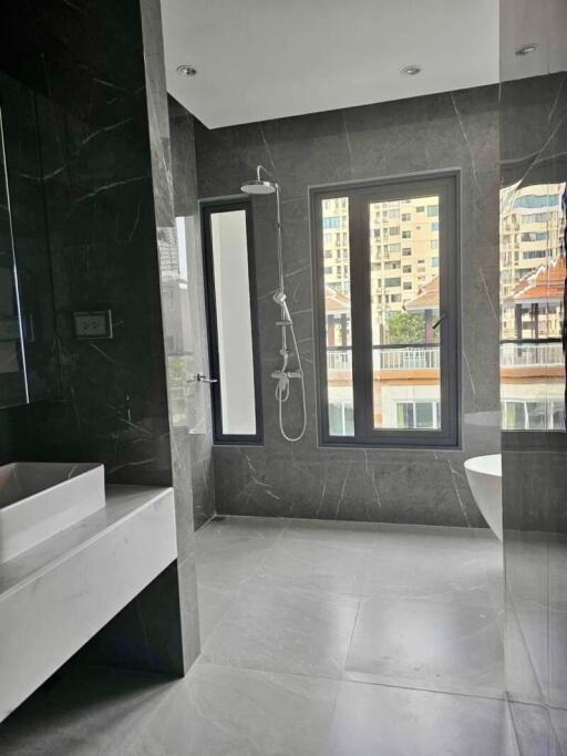 Modern bathroom with marble walls and floors, featuring a standalone bathtub and a separate shower area