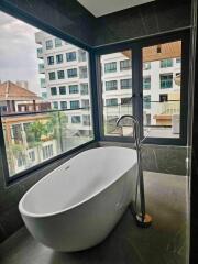 Modern bathroom with a standalone bathtub and large windows overlooking the city