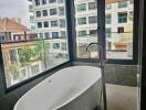 Modern bathroom with a standalone bathtub and large windows overlooking the city