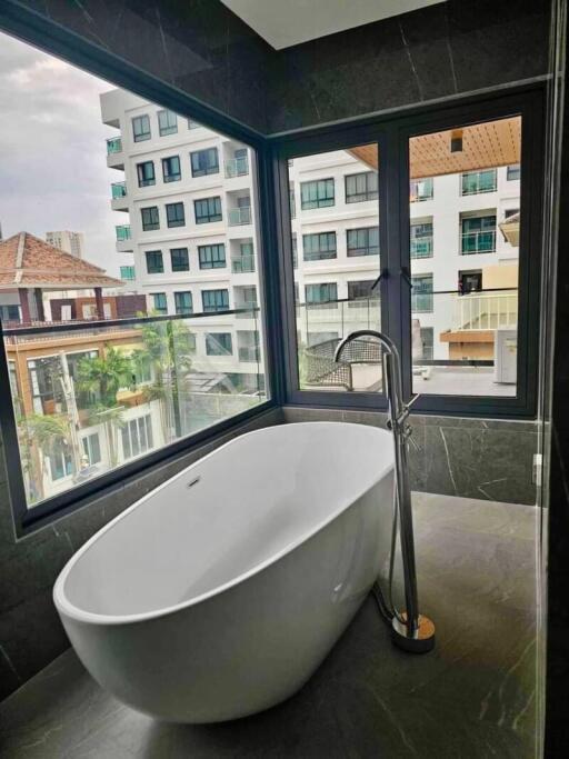 Modern bathroom with a standalone bathtub and large windows overlooking the city