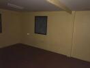 Dimly lit empty room with wooden flooring and a single window
