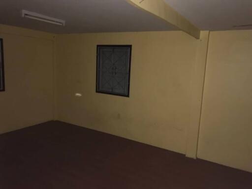 Dimly lit empty room with wooden flooring and a single window